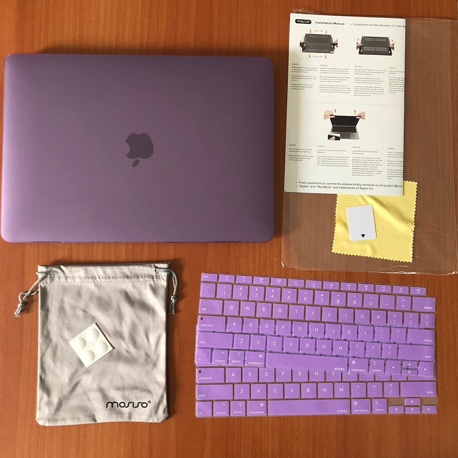 reviewer photo of a full laptop protector set: two purple laptop shells, two silicone purple keyboard covers, a screen protector, cleaning cloth, and bag