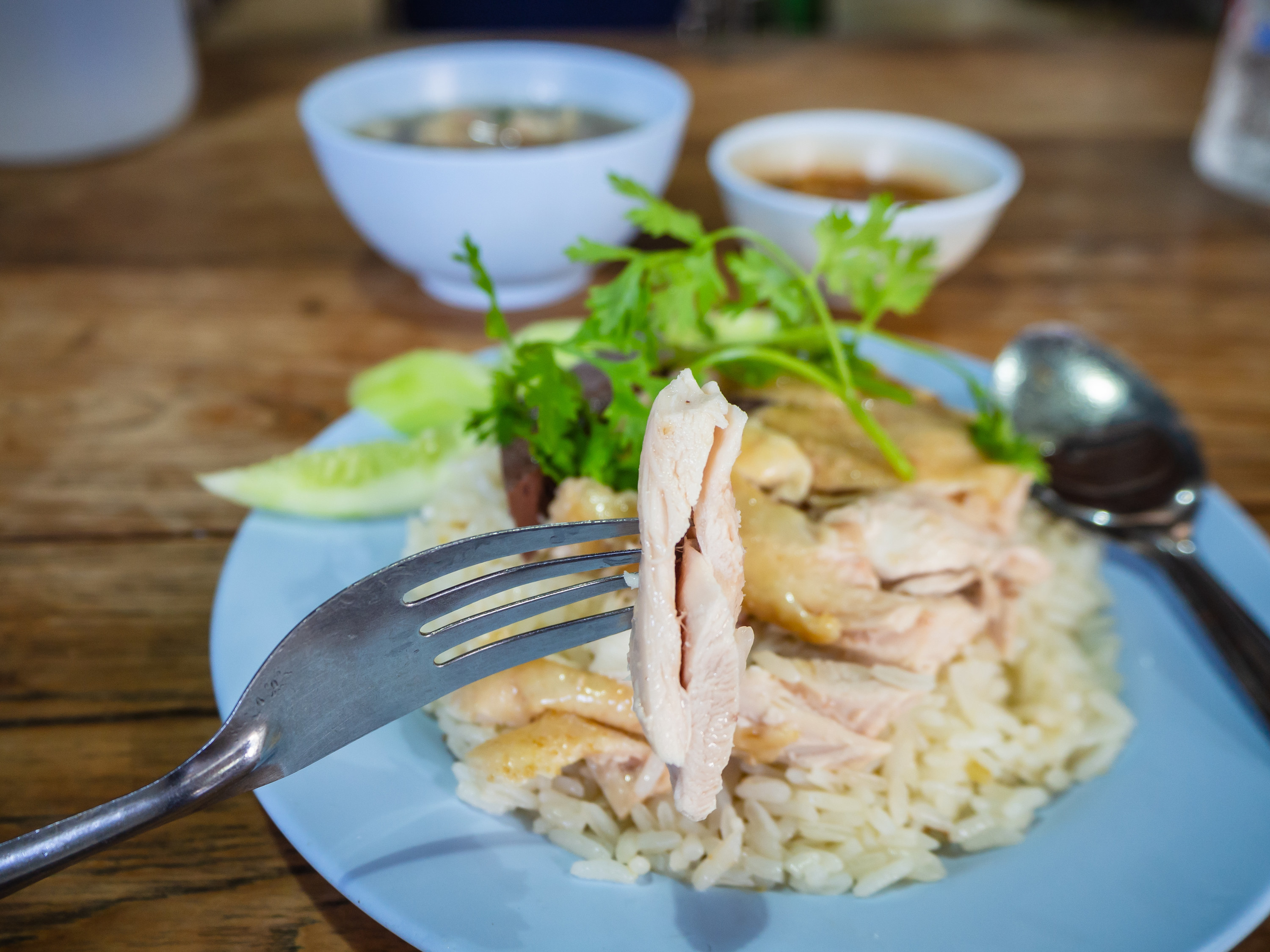 plate of chicken rice with a fork holding a piece of chicken