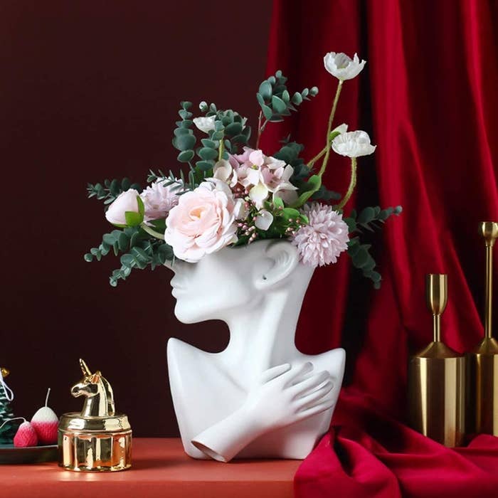 a vase shaped like a bust and filled with flowers