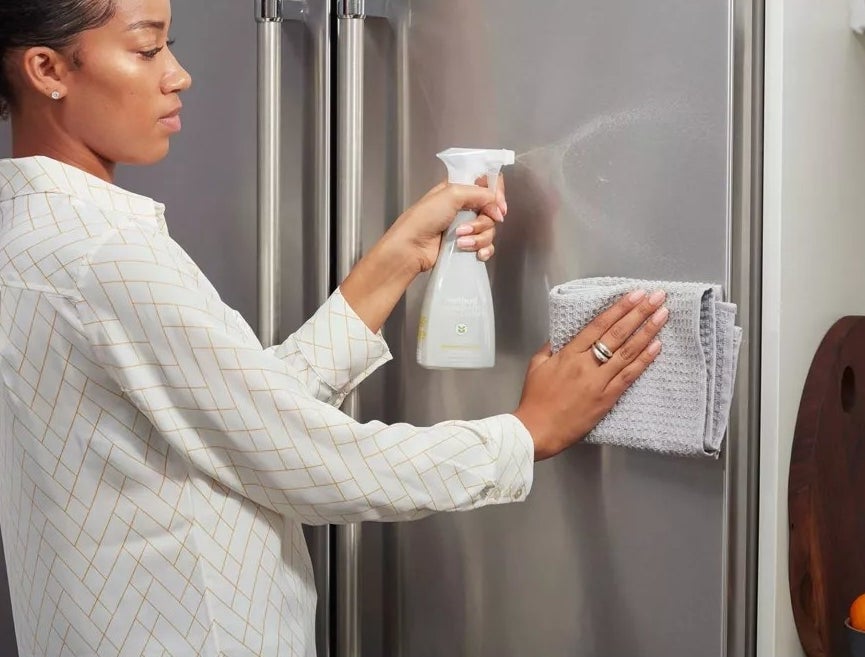 A model using the stainless steel cleaner on a refrigerator