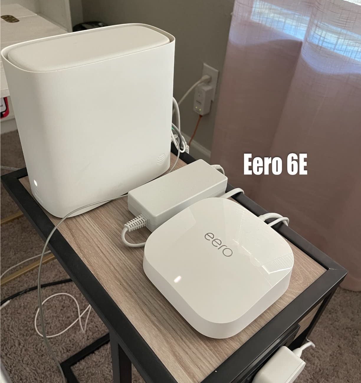 a reviewer showing the eero next to their larger AT&amp;amp;T router