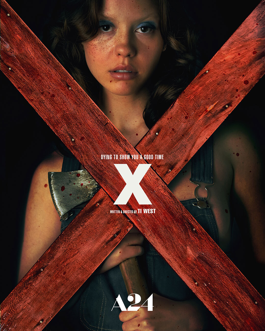 The movie poster for &quot;X.&quot; Mia Goth&#x27;s character Maxine Minx stands holding an axe with blood splatters. There are two red boards that make an X, spanning the entire poster
