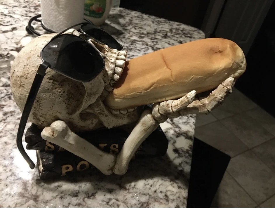 A skeleton stuffing a bun in its mouth