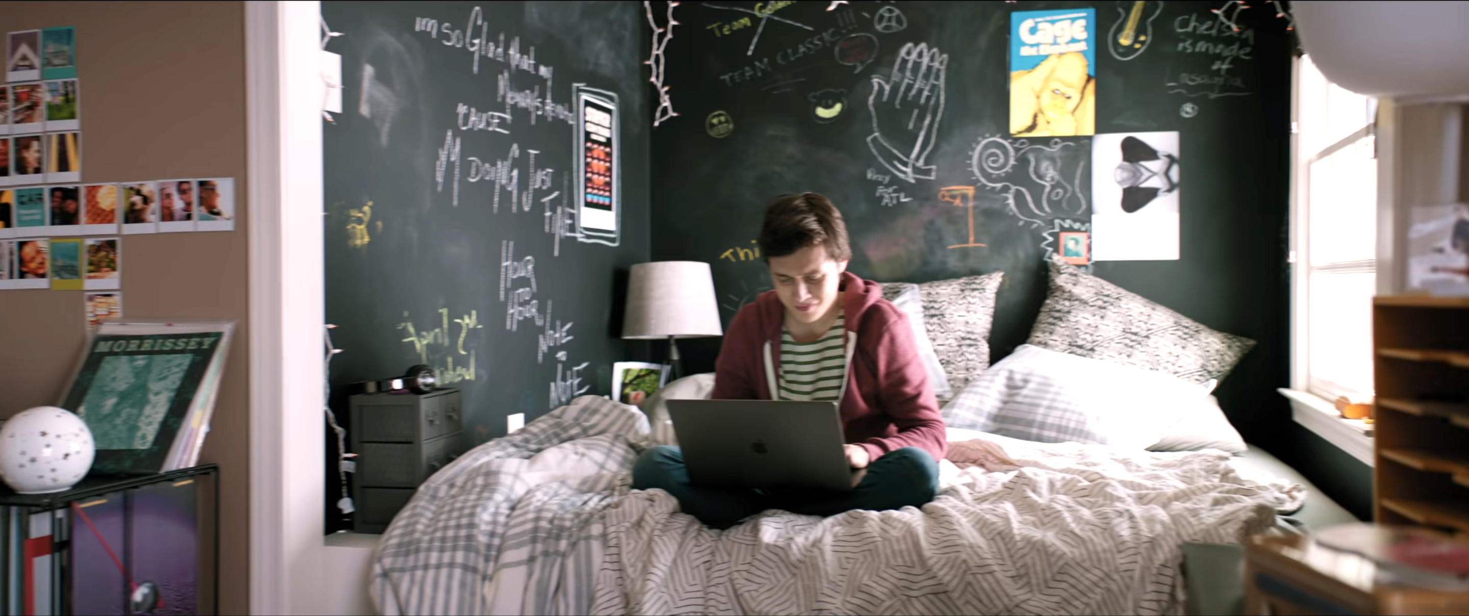 a woman sitting on a bed with chalkboard walls behind her