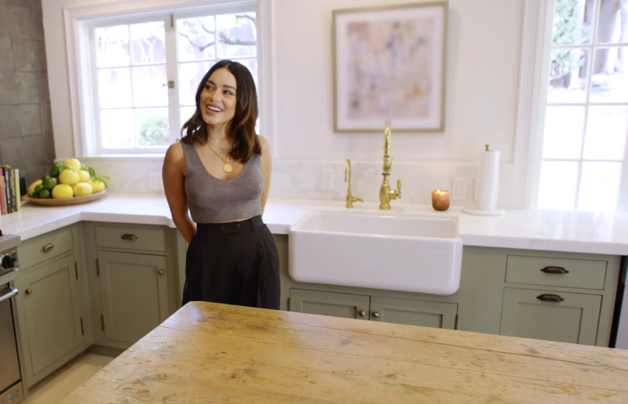 a woman smiling in a kitchen with a farmhouse sink