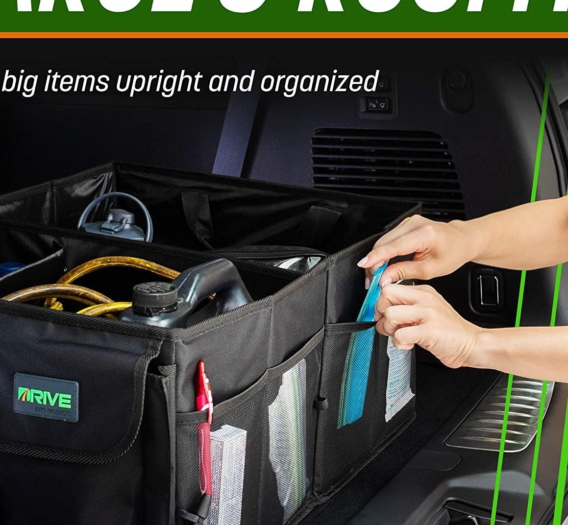 the organizer in a trunk filled with things and someone putting something in one of the pockets