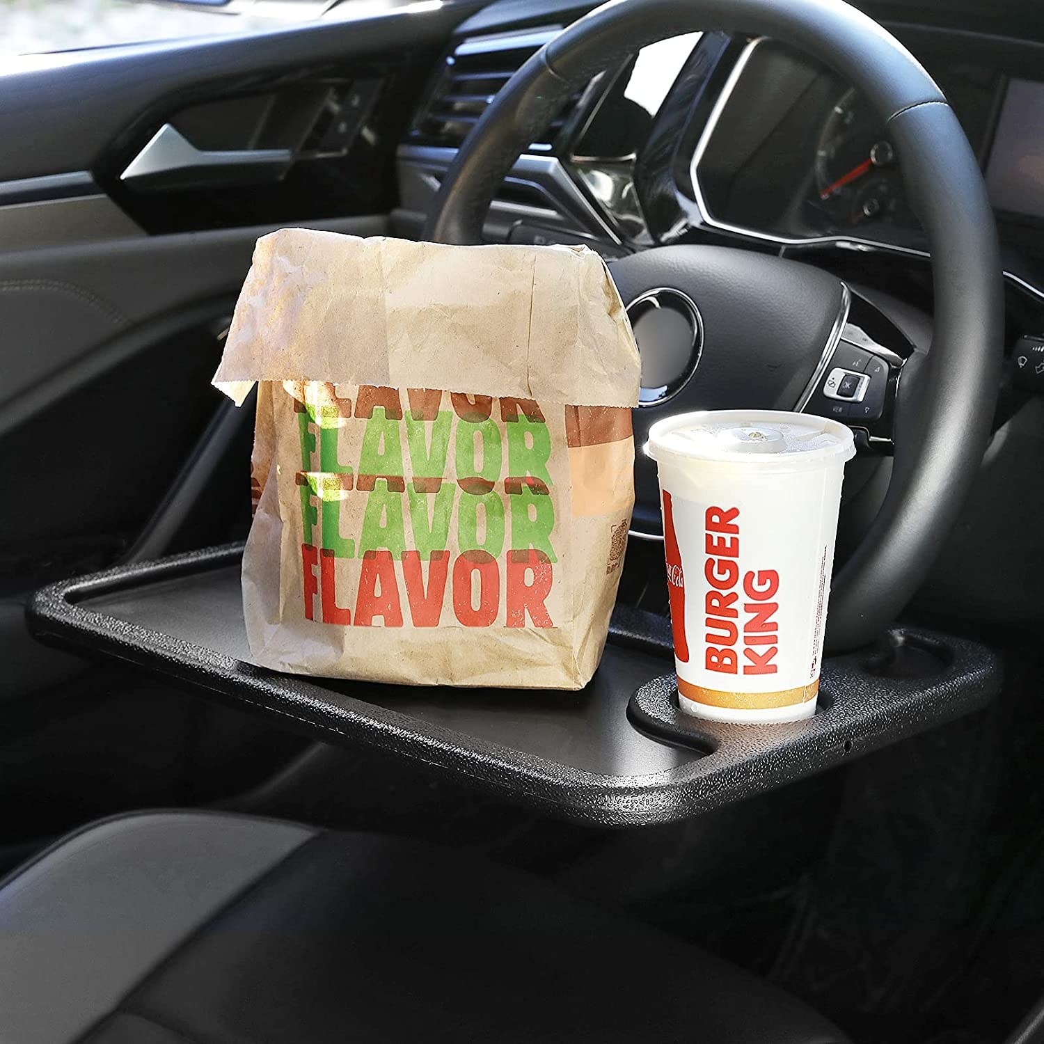 fast food on the steering wheel tray in a car
