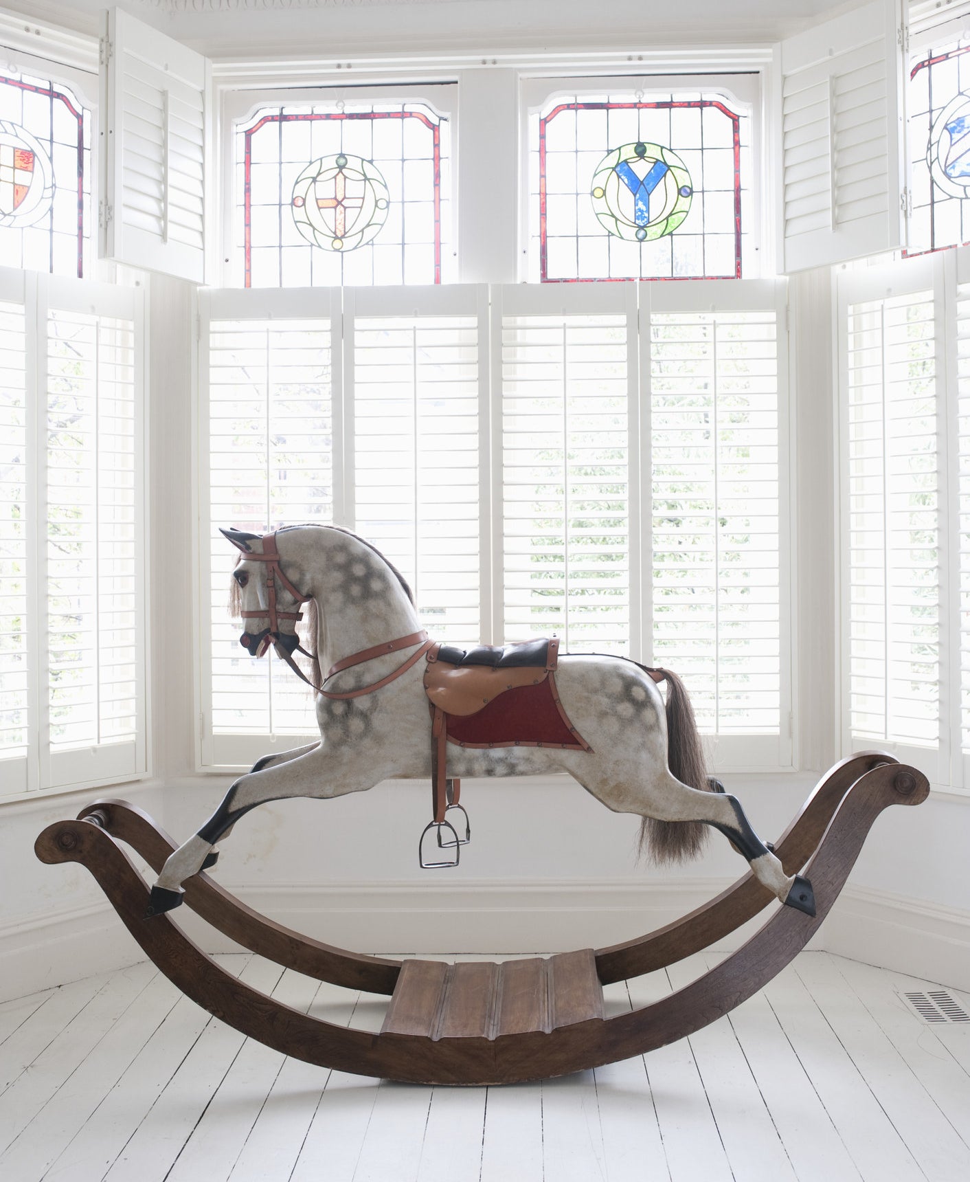 A rocking horse in front of a bay window