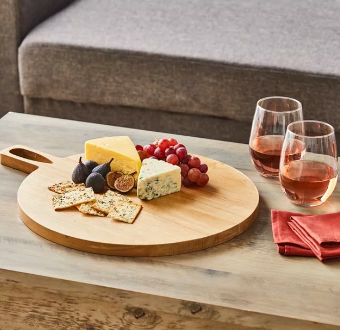 Wooden board with charcuterie, wine glasses and napkins