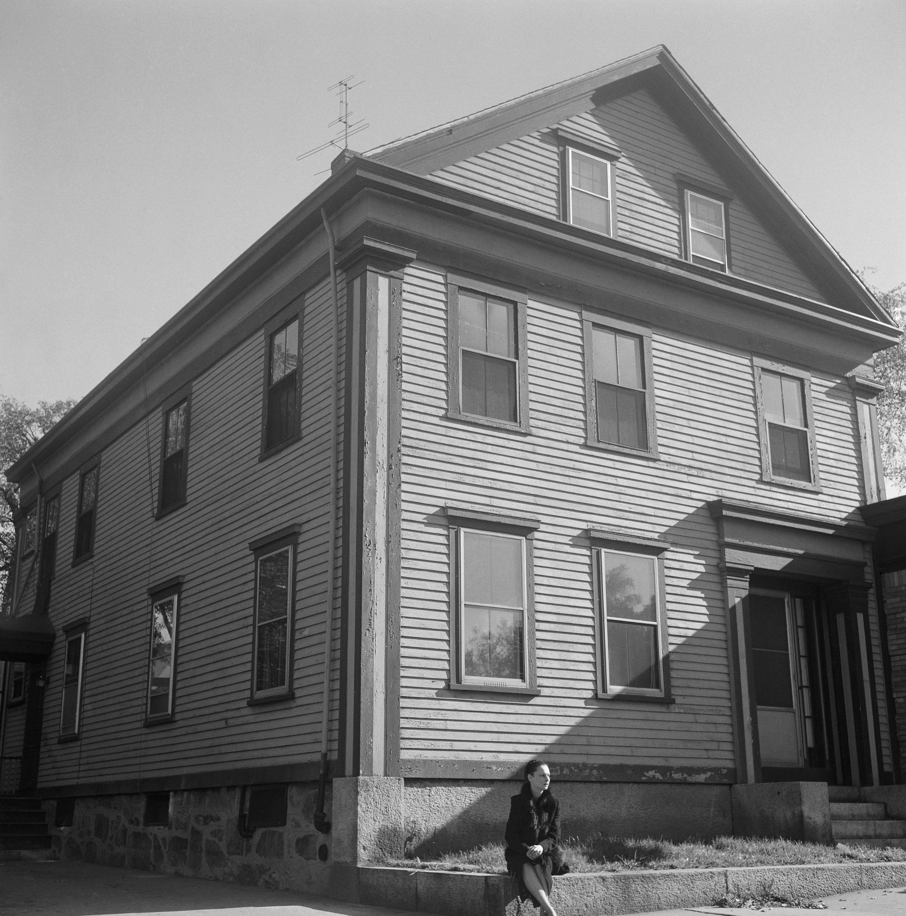 Woman sits in front of house