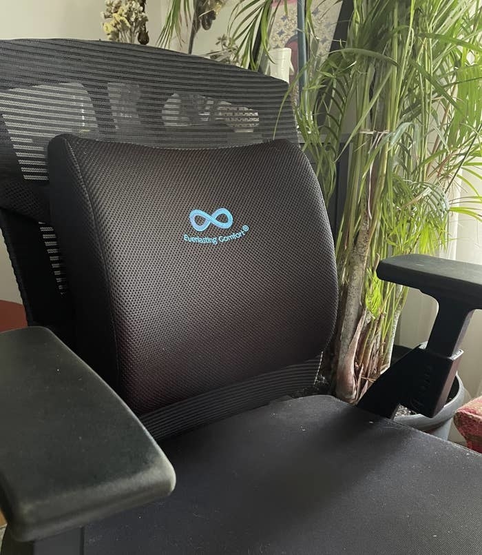 An office chair with a lumbar support pillow on the back