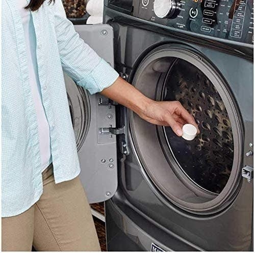 a person about to put a tablet into a washing machine