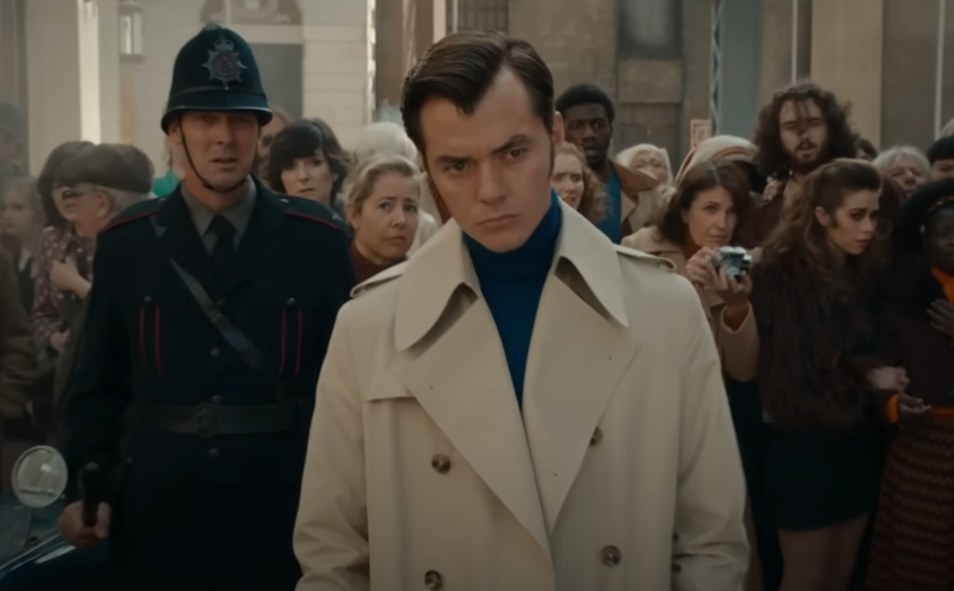 Jack Bannon as Alfred Pennyworth in front of a crowd of people looking at something
