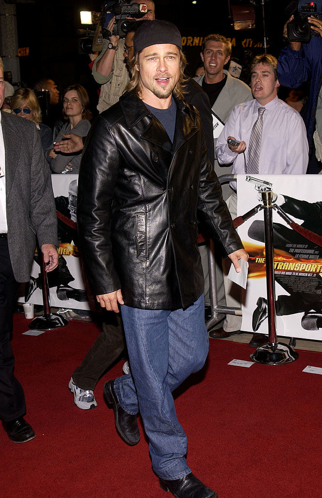 Brad Pitt on the red carpet with paparazzi behind him