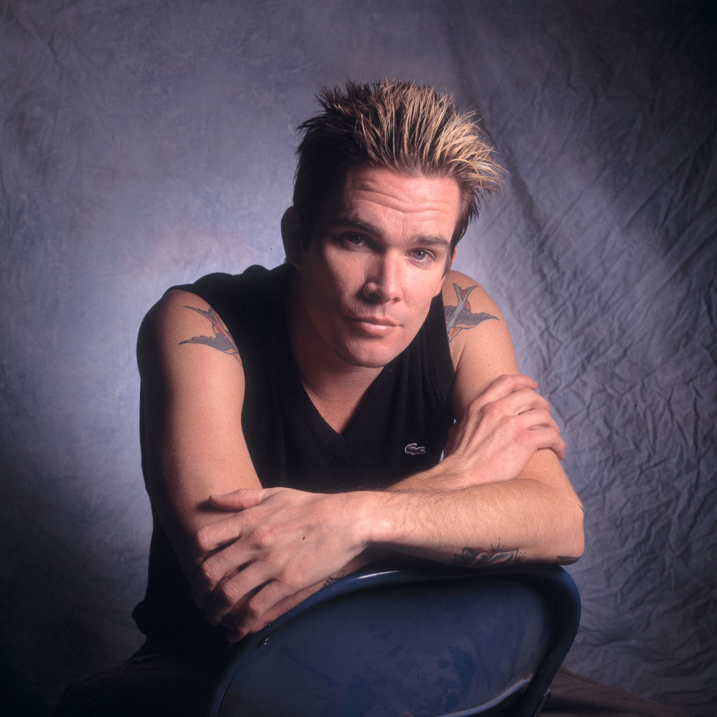Mark McGrath bending down with his arms crossed