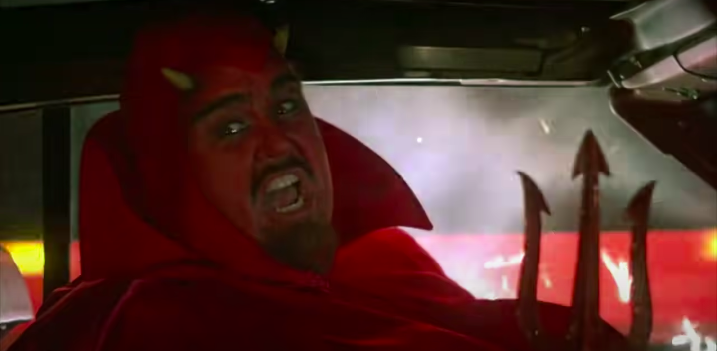 A man in a devil costume drives a car