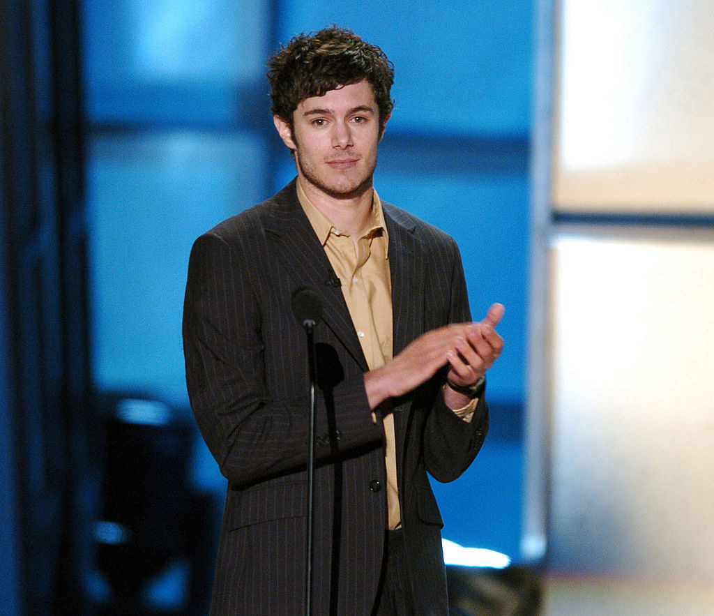 Adam Brody clapping onstage in front of a mic