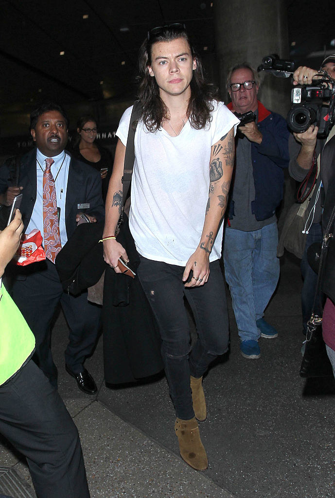 Harry Styles walking with a crowd of people behind him