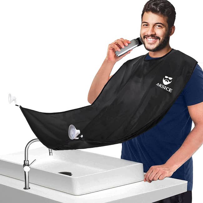 A model wearing the beard trimming catcher around their neck like a bib, but with the other end suction cupped to a mirror