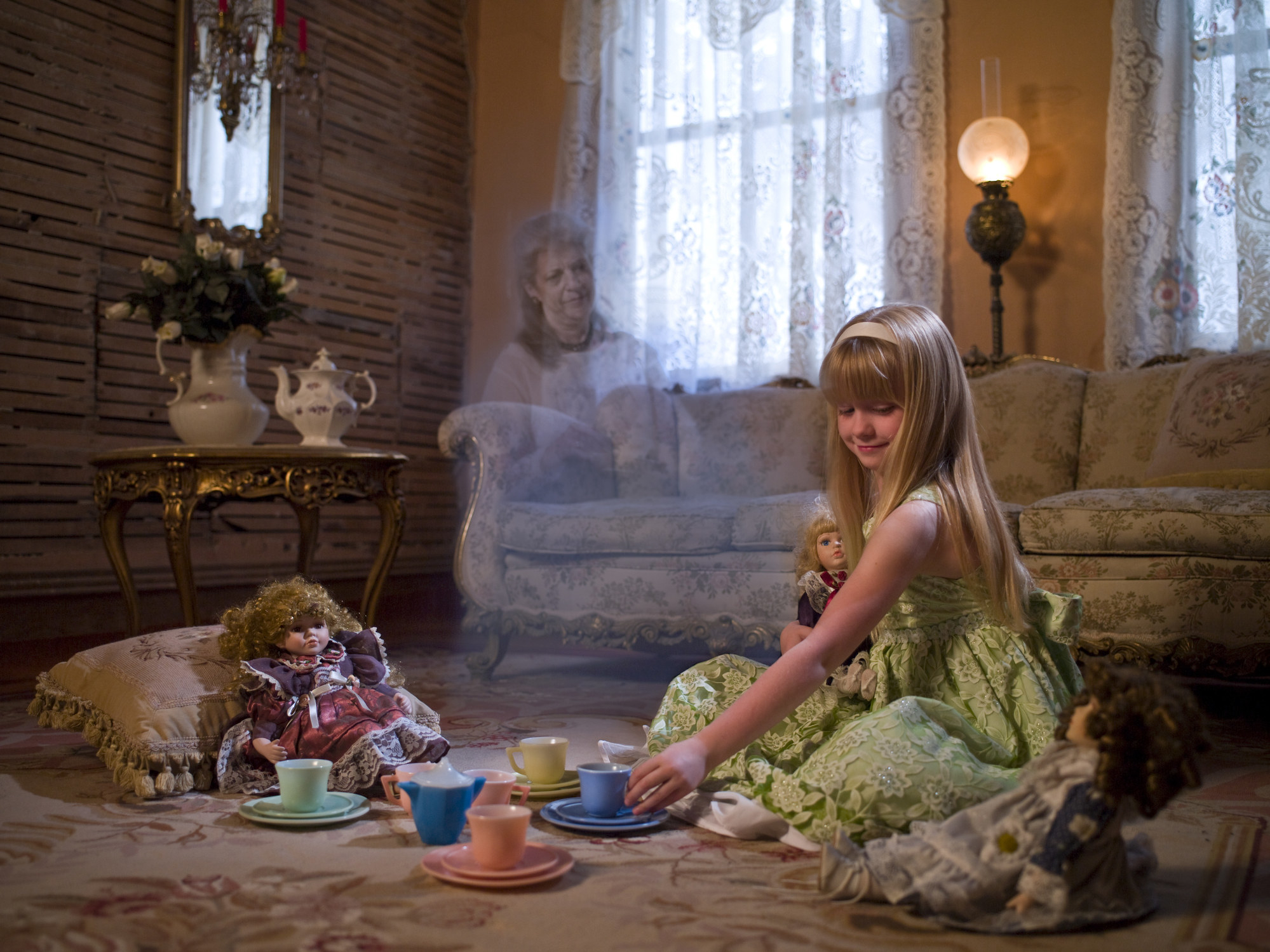 A ghost in the background as a little girl plays with a tea party set