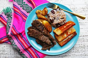 Carne Asada, Queso Frito, Fried Plantains and Rice and Beans on a Blue Plate with a Pink Napkin