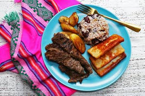 Carne Asada, Queso Frito, Fried Plantains and Rice and Beans on a Blue Plate with a Pink Napkin