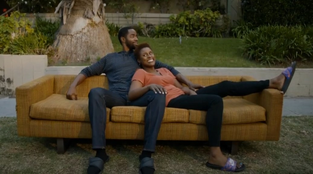 Issa Rae as Issa Dee and Jay Ellis as Martin cuddled up on a couch together outside