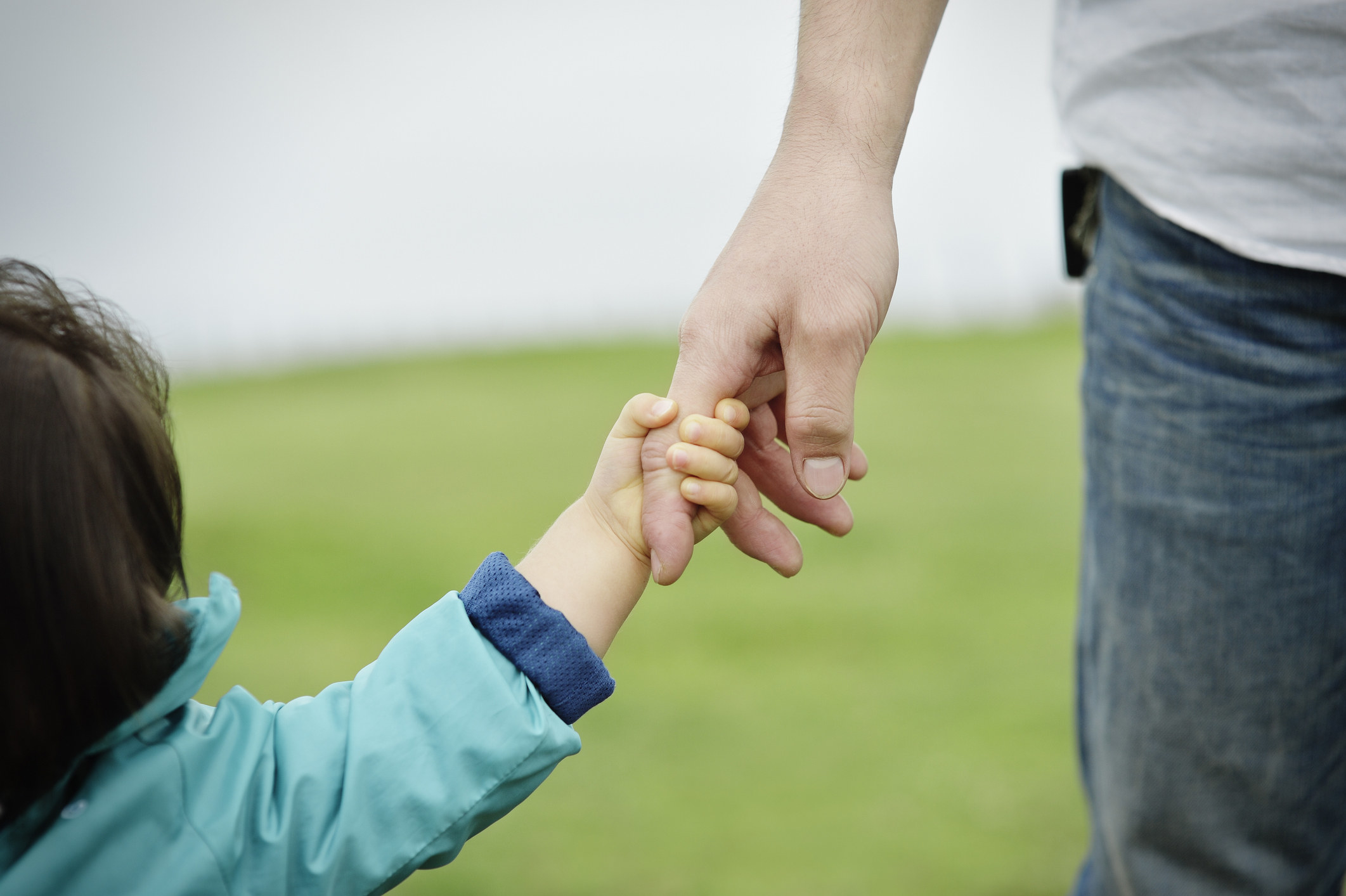 close up of a child&#x27;s hand wrapped around an adult&#x27;s finger