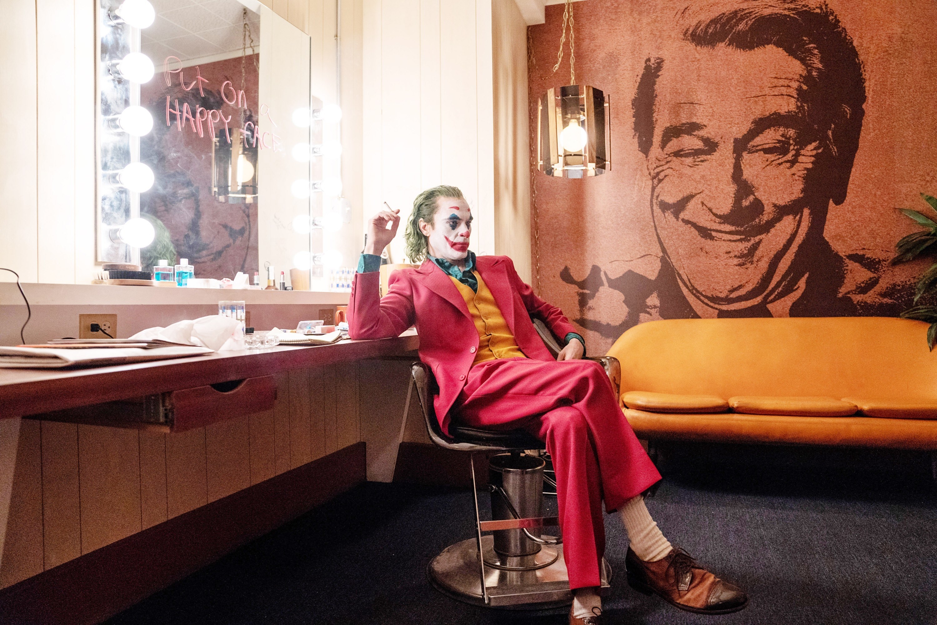 华金·菲尼克斯（Joaquin Phoenix）坐在椅子上拿着香烟的小丑