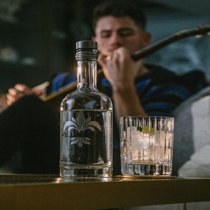 a bottle of villa one tequila and nick jonas in the background