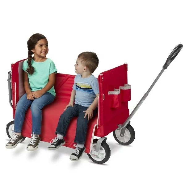two children sit in the red wagon