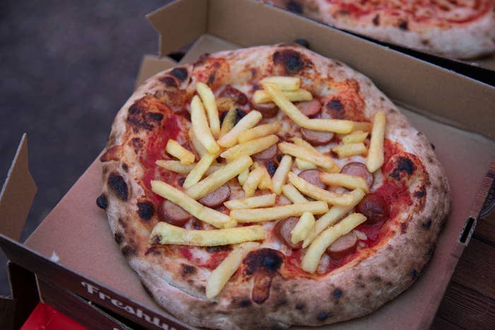 A pizza topped with French fries.