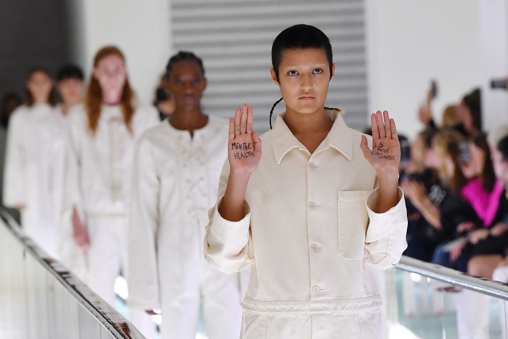 Bones on the catwalk holding up the palms of their hands and showing the message