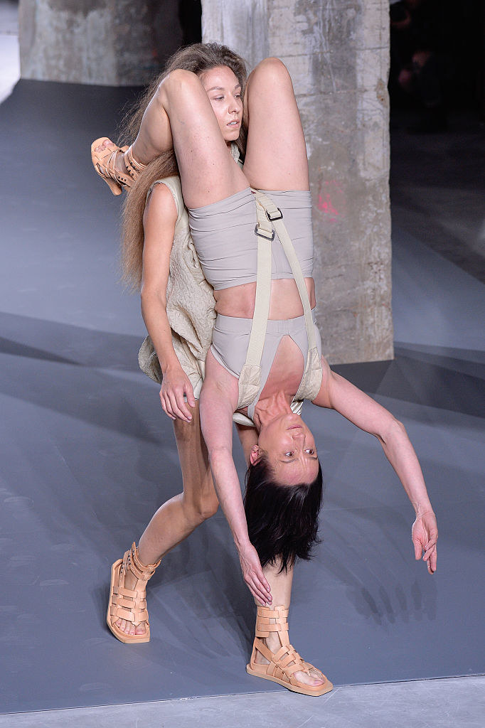 Model on the runway with another model hanging from their shoulders in front of them