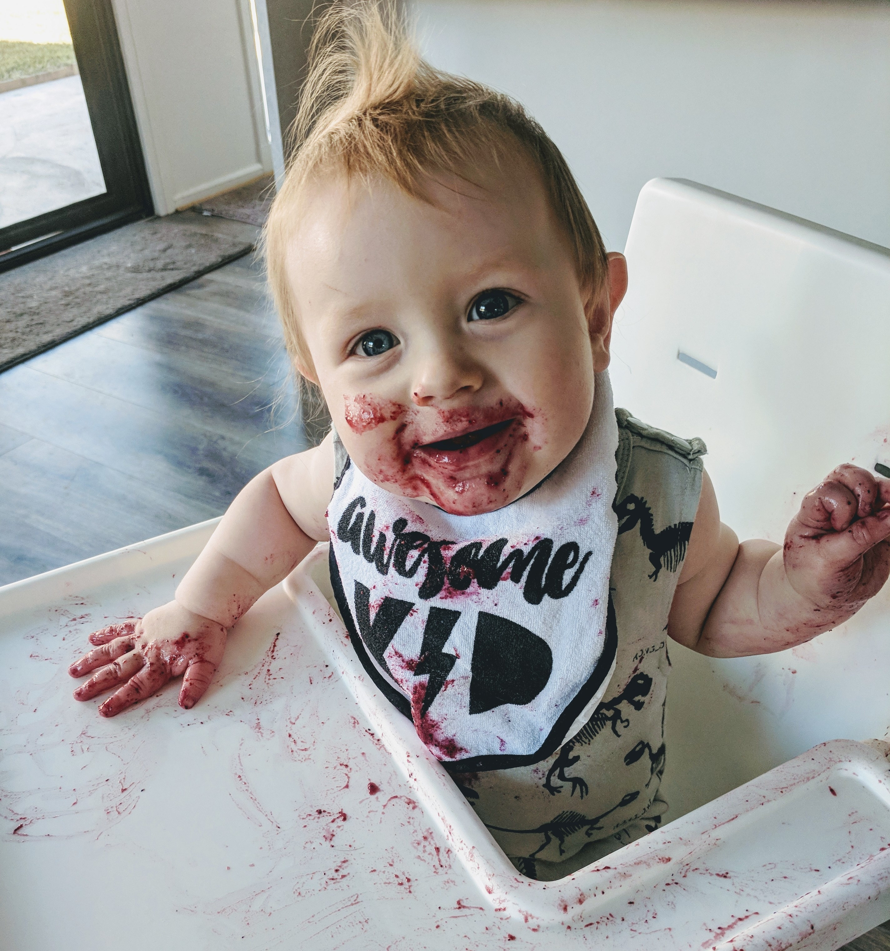 A baby in a high chair with food on their face