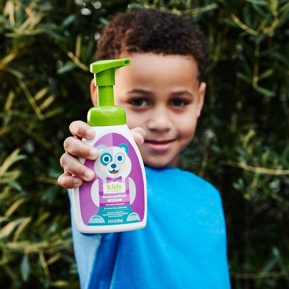 a kid holding a bottle of the kids by babyganics foaming hand sanitizer with a panda on the front
