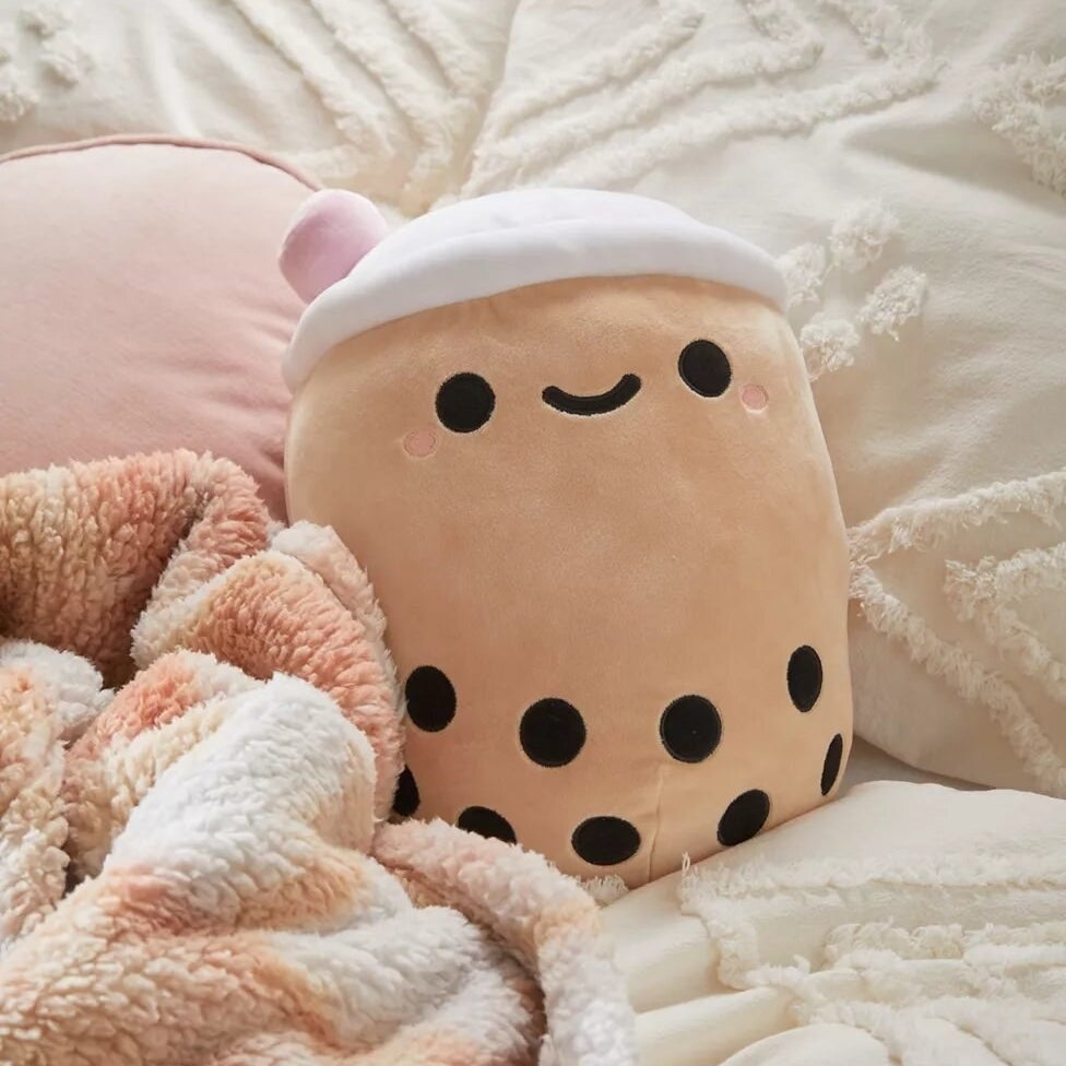 the plushie on a bed beside a blanket