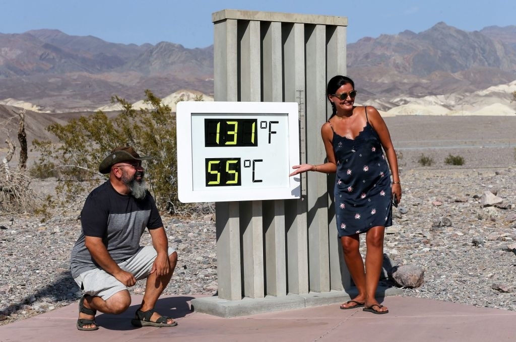 A man and a woman against a rocky backdrop stand by a sign giving the temperature in Celsius and Fahrenheit