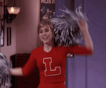 Rachel in a cheerleading outfit jumping happily from an episode of friends