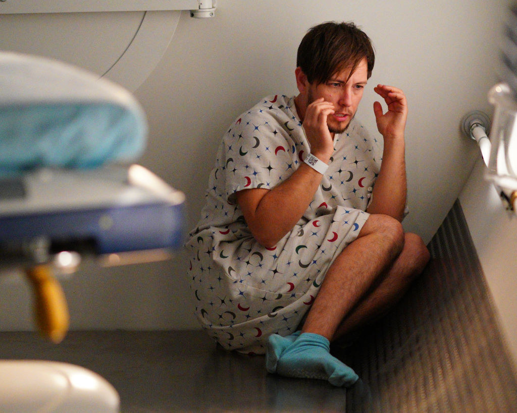 man in a hospital gown sitting on the floor