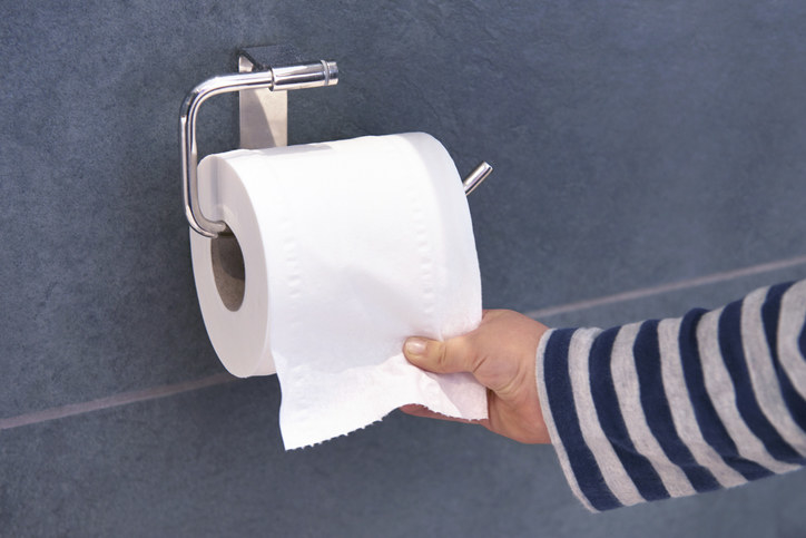 Toiler paper on a roll with the paper going over and a hand grabbing it