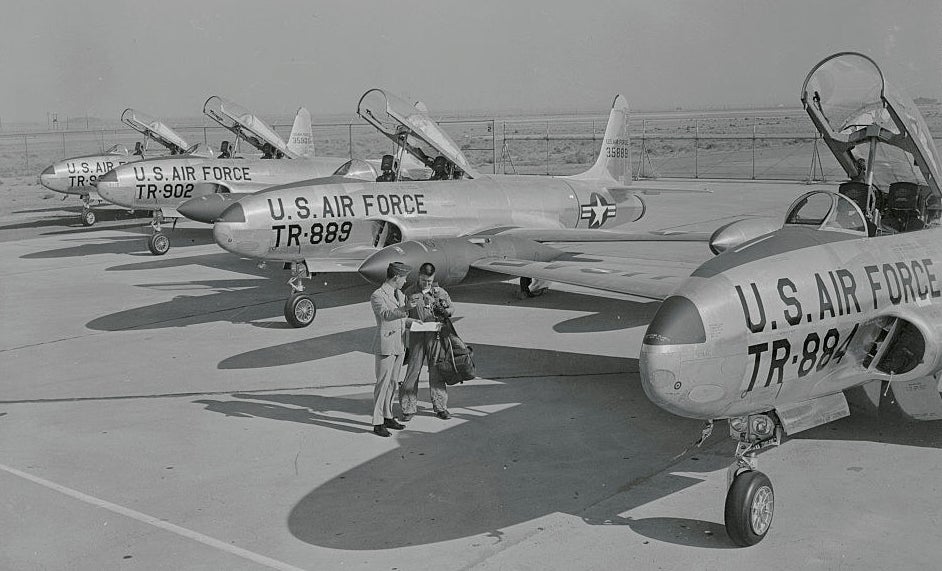 Two pilots standing in front of planes in palmdale, CA in the 1950s