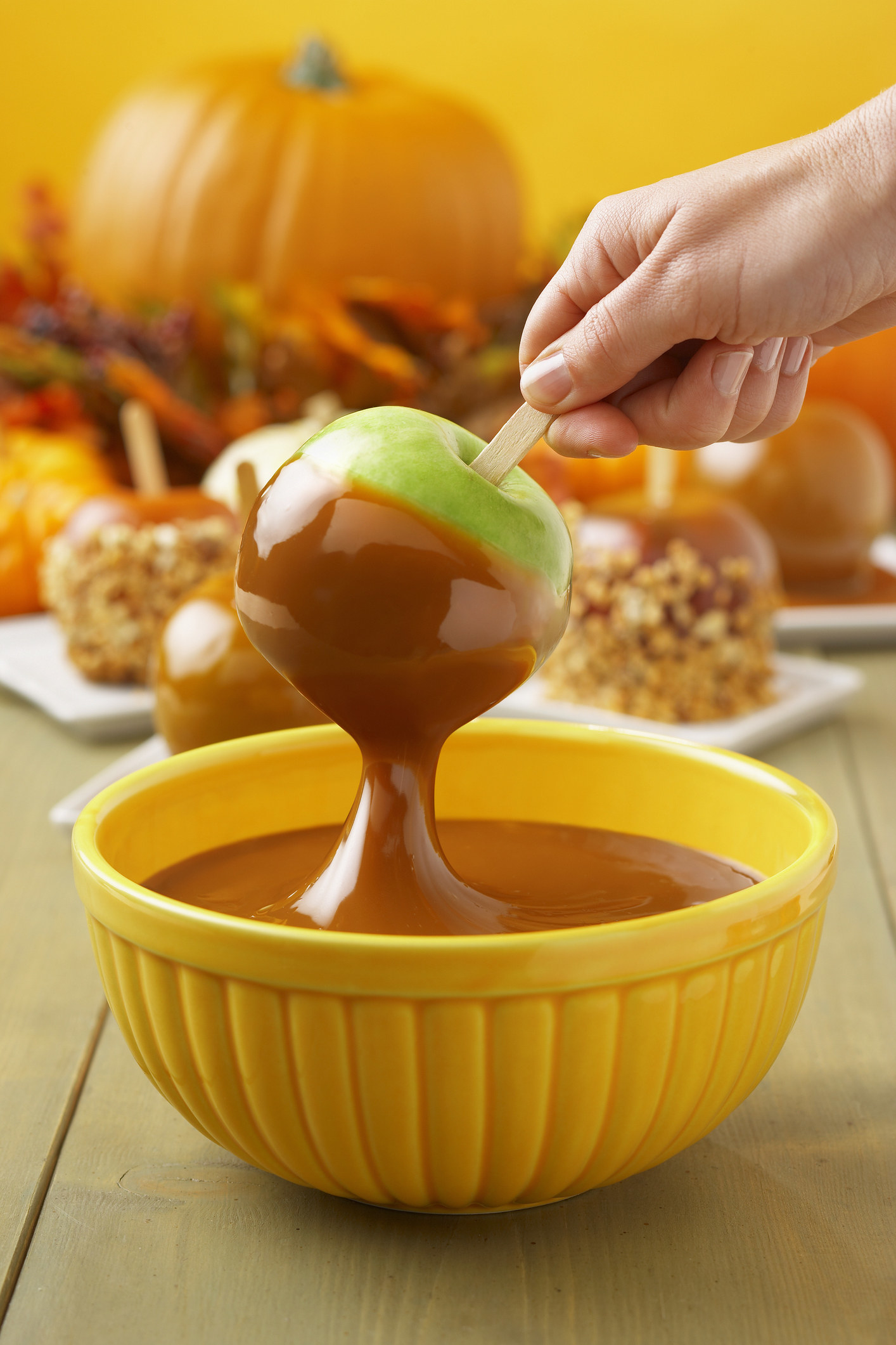 hand dunking an apple into a bowl of caramel