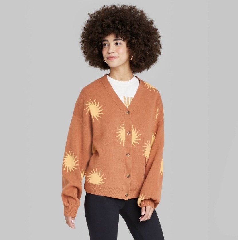The model wears the orange sweater with golden yellow suns