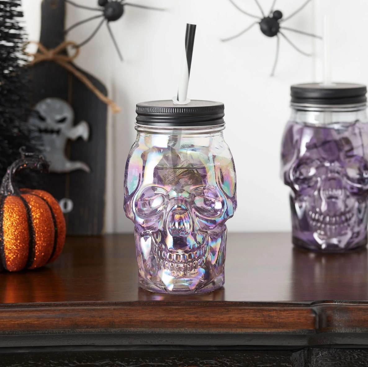 iridescent glass skull shaped cup with black lid and striped straw