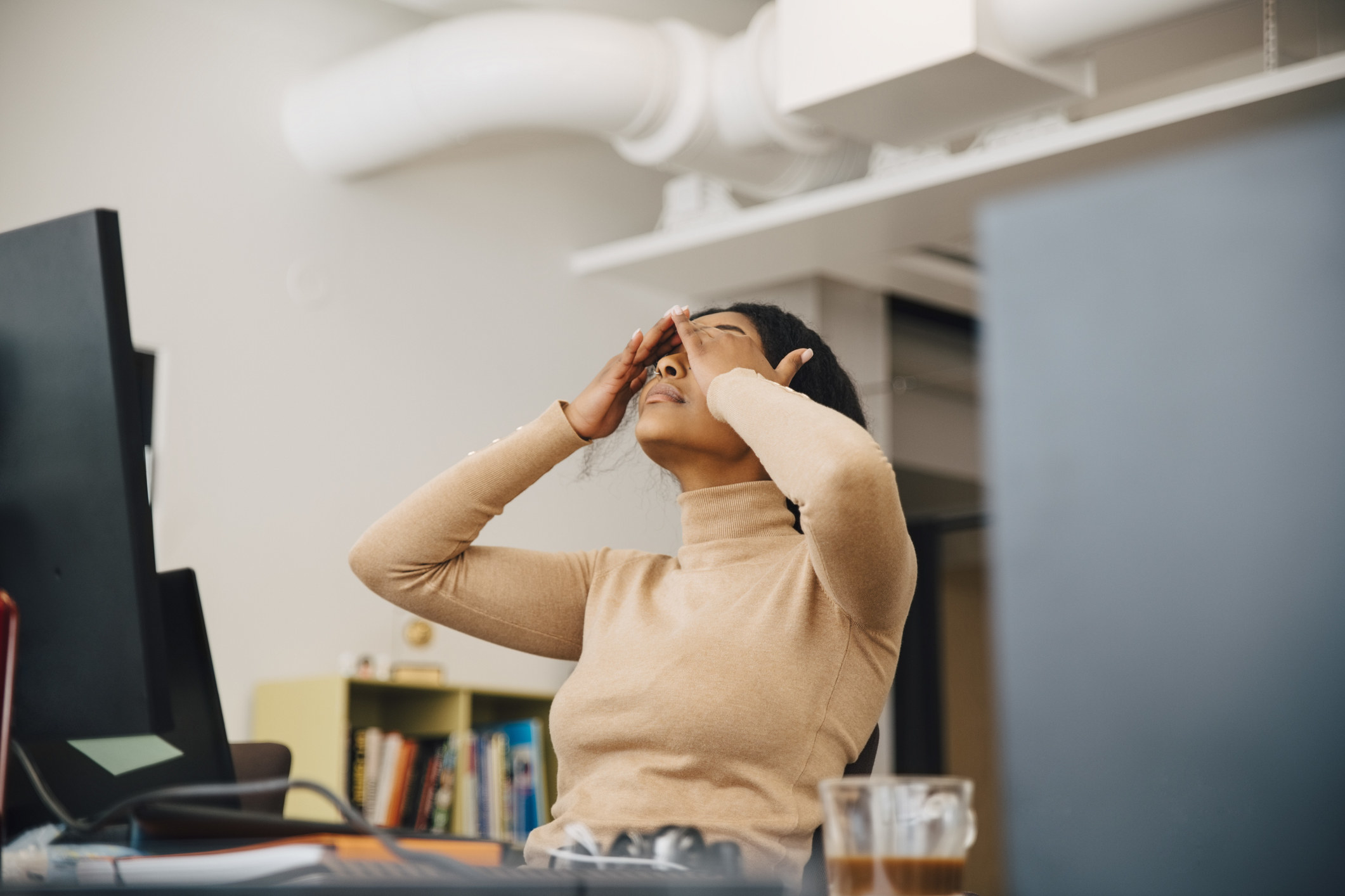 A woman massaging her eyes at her desk