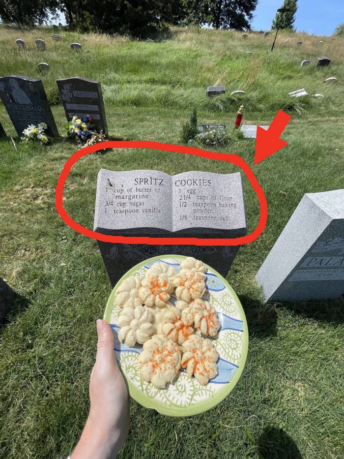 The plate of cookies being held in front of a gravestone with a recipe for Spritz Cookies inscribed on it