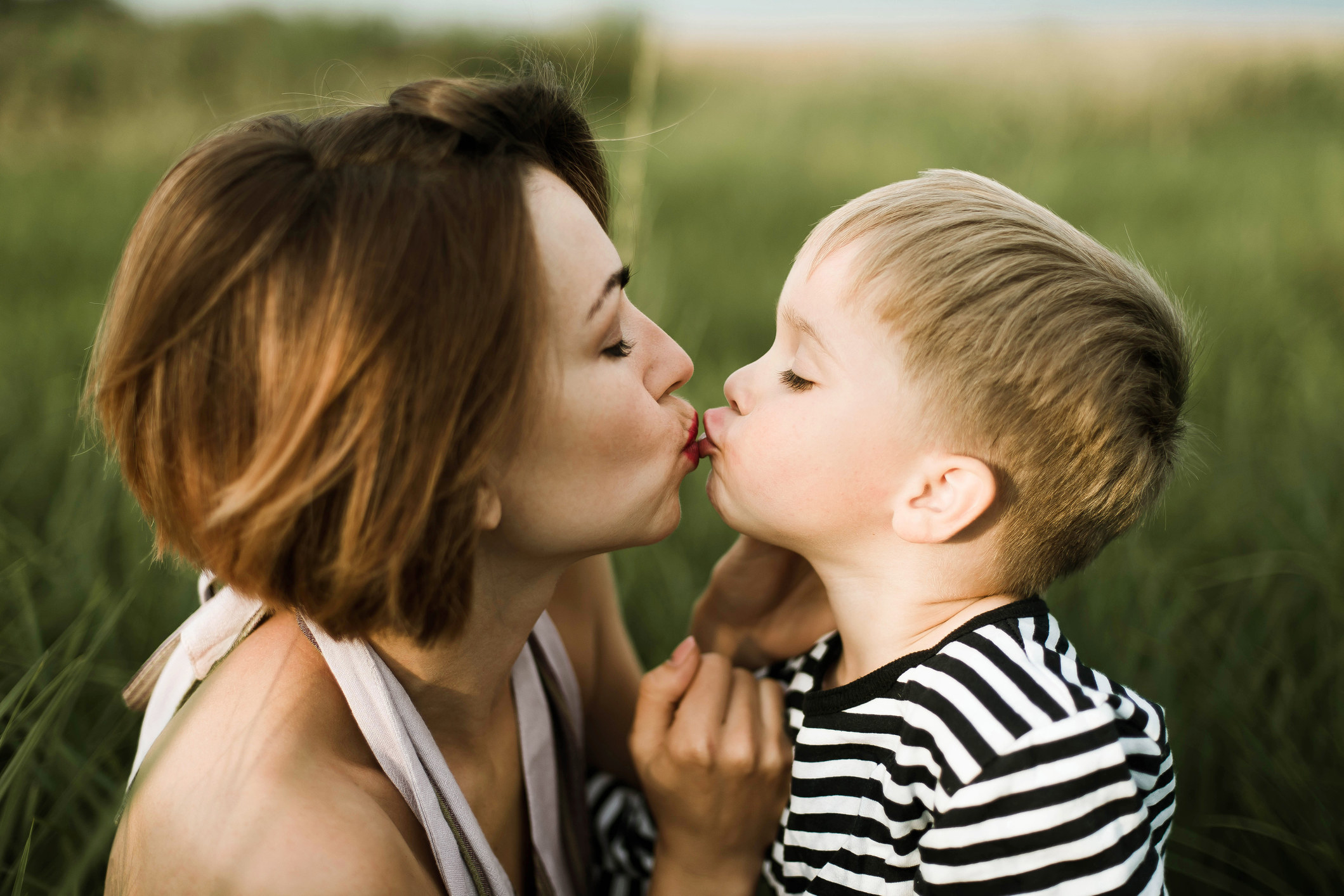 A mom kissing her son on the lips