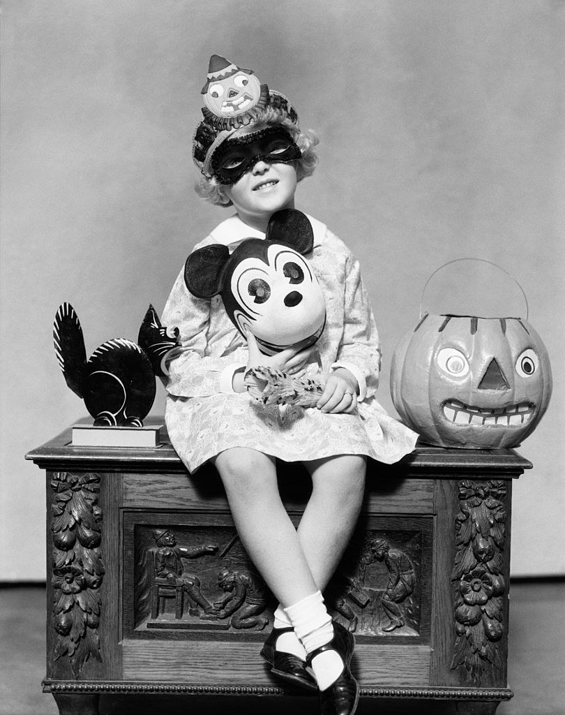 A child holding a Mickey Mouse mask