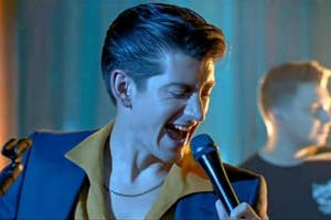 alex turner, lead singer of arctic monkeys, sings into a microphone with mouth wide open